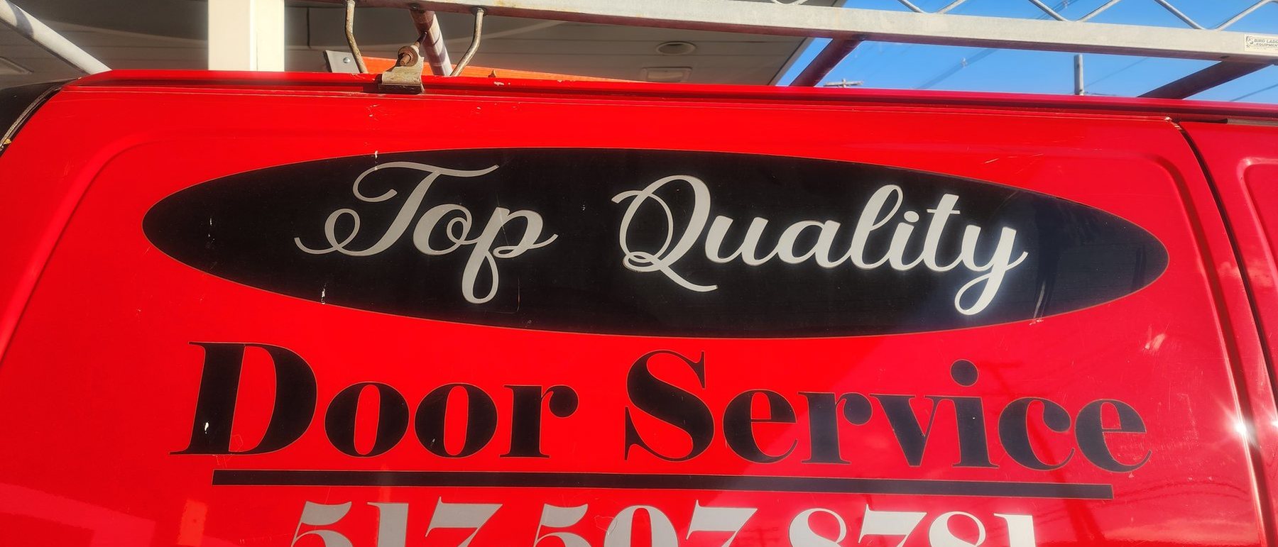 The red Door Service van door with the Top Quality Door Service lettering and phone number
