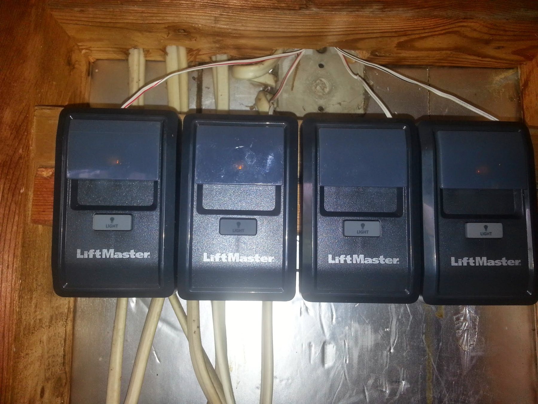 Four LiftMaster garage door opener wall controls mounted in a row on a garage wall